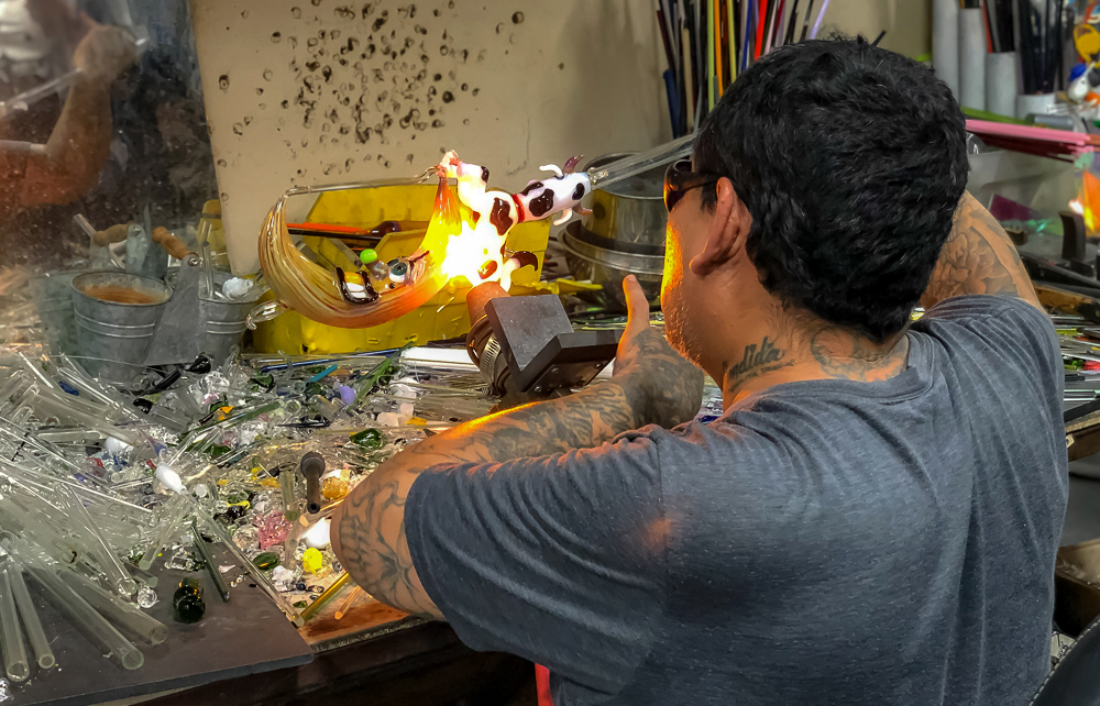 Worker torching the end of a glass pipe