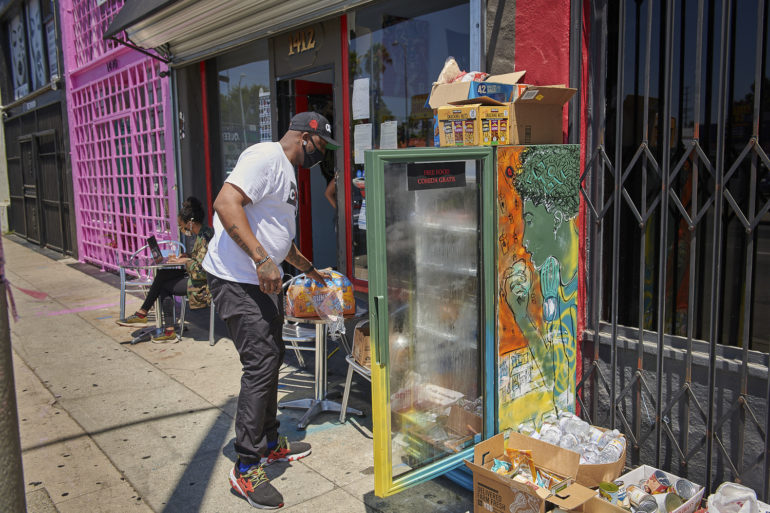 A man stocks the community refrigerator located outside Little Amsterdam Coffee.