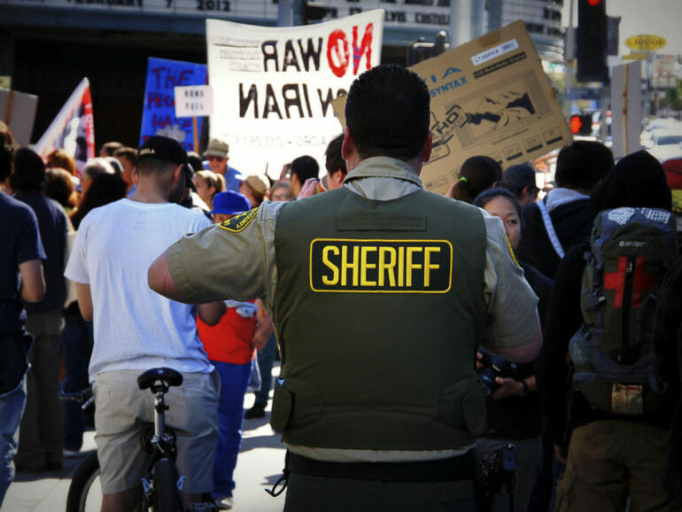 A Los Angeles Sheriff’s Department deputy watches a crowd at an anti-war protest in 2012.