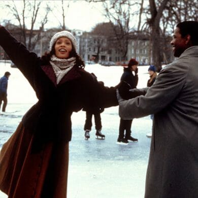 A woman and man ice skate together on a frozen outdoor lake.