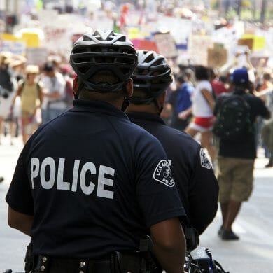 A Los Angeles Police Department Officer faces a crowd of protesters.